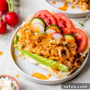 hoagie roll topped with pulled chicken, vegetables and sauce