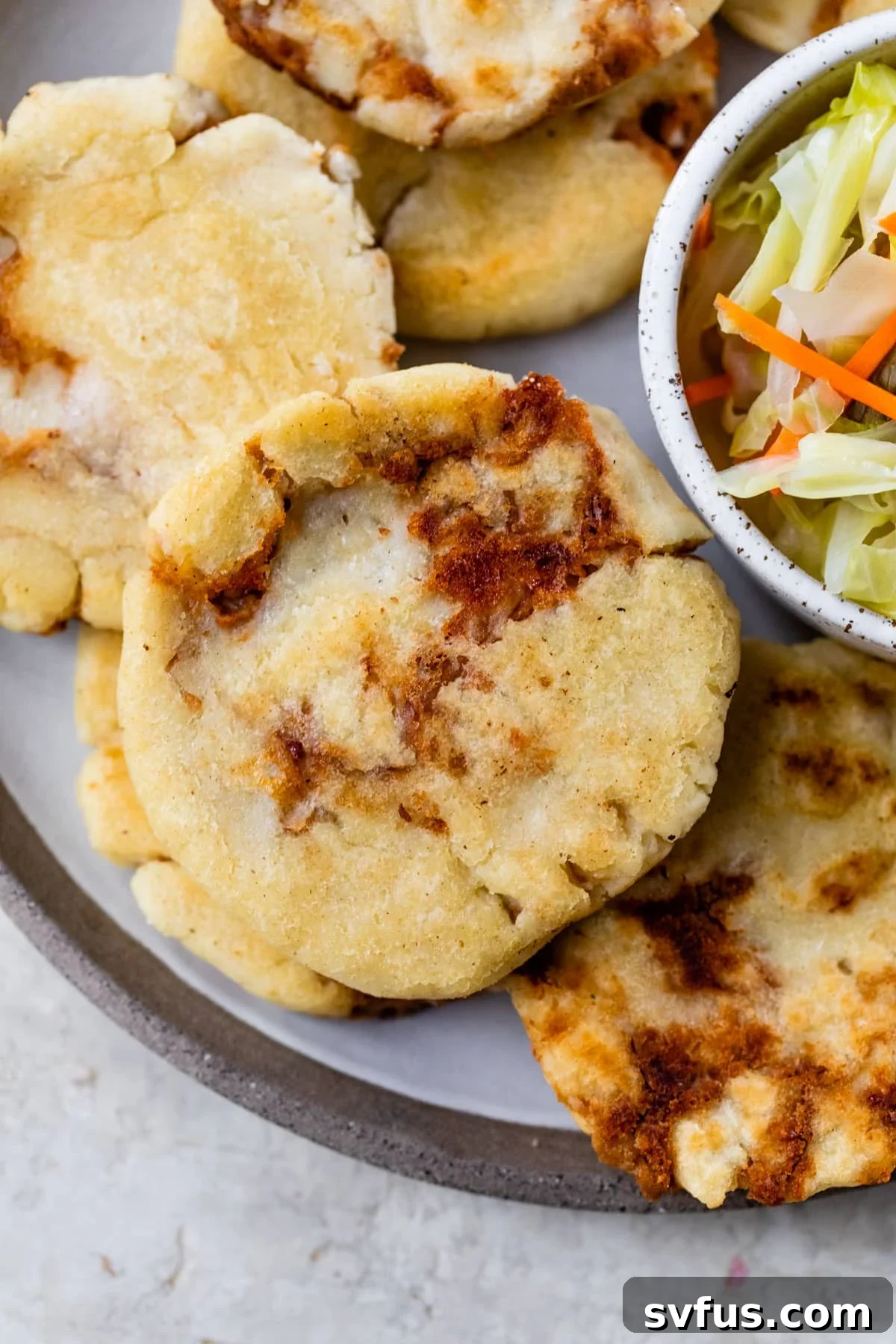 discs of cooked dough on a plate beside a small dish of cooked cabbage and carrots