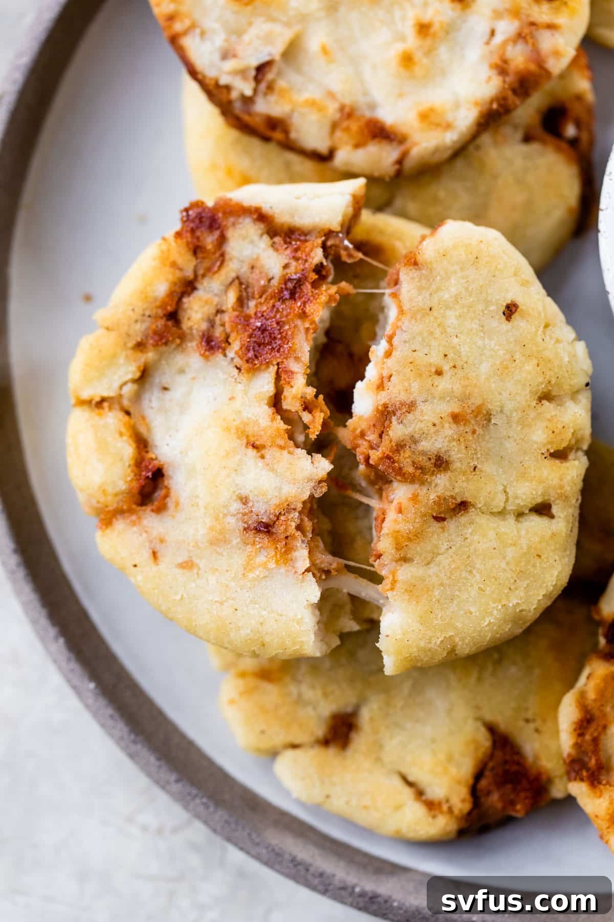 a disc of cooked dough pulled apart revealing melted cheese inside