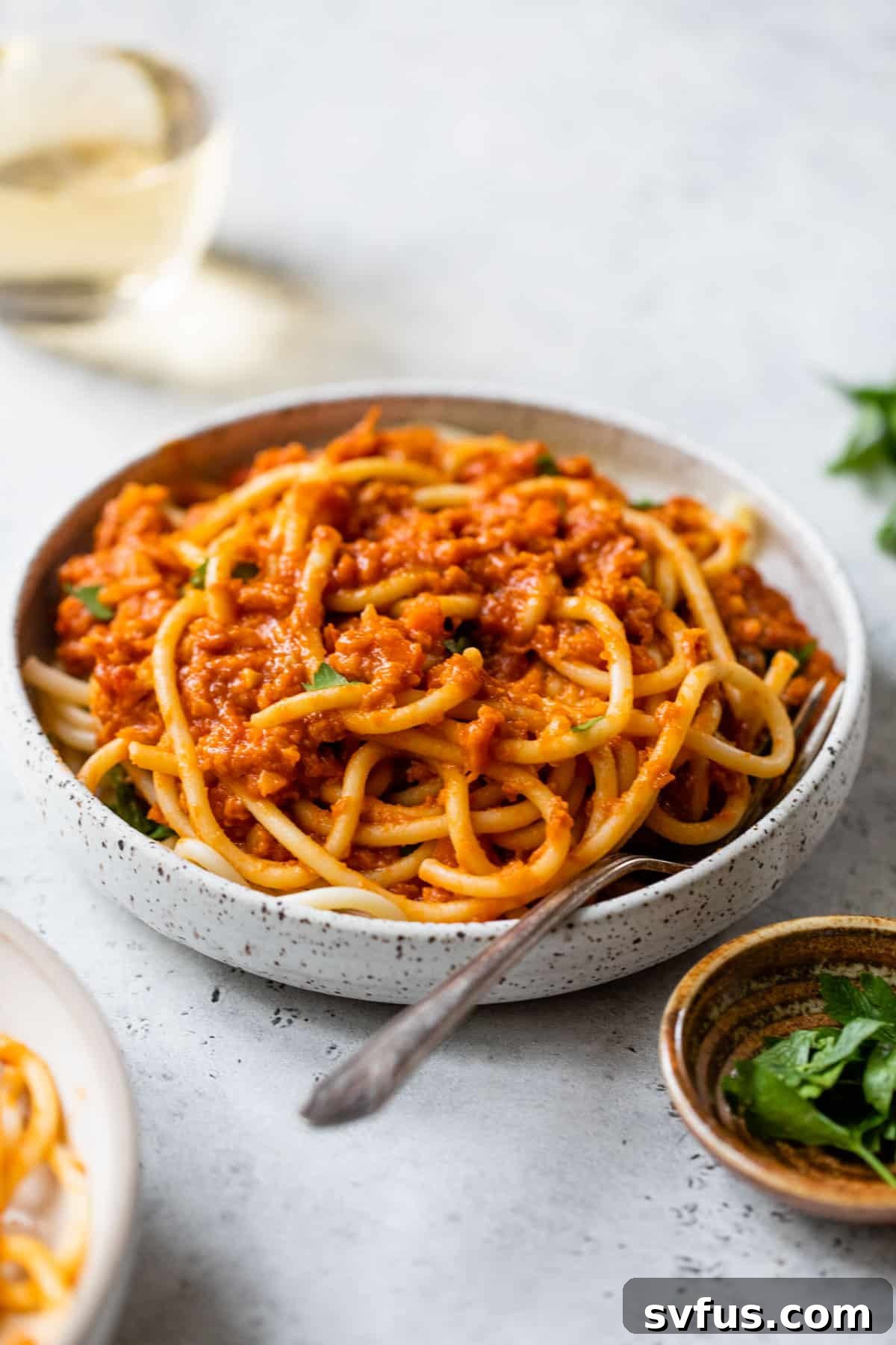 A beautiful bowl of pasta with the rich, red lentil ragu, placed beside a refreshing glass of white wine, ready to be enjoyed.