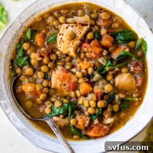 a bowl of soup with cooked diced chicken, green onions and vegetables