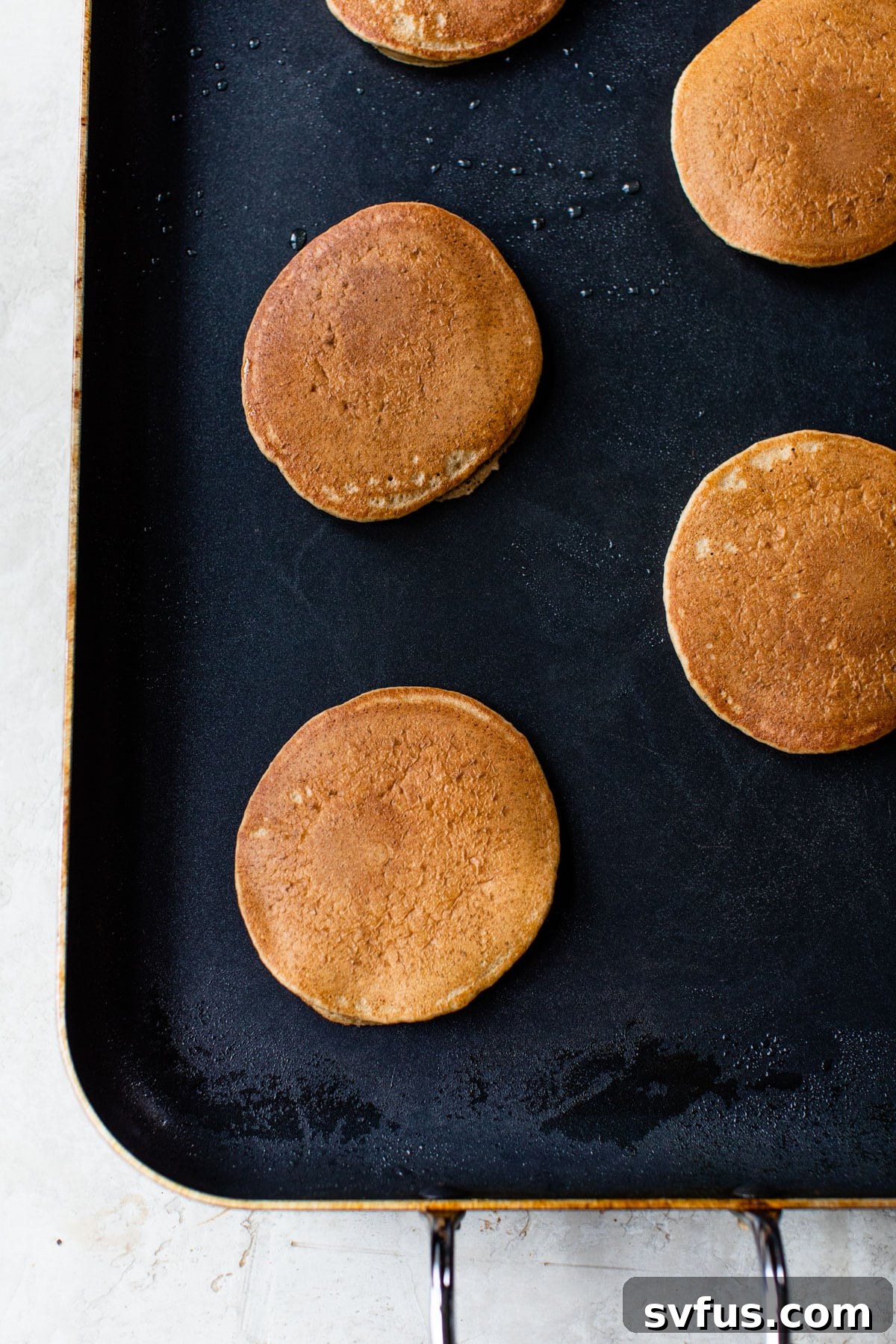multiple golden-brown banana yogurt pancakes sizzling on a hot griddle, bubbles forming on the surface