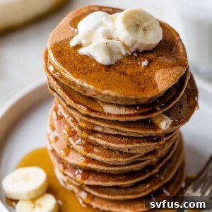 stack of pancakes on a plate topped with yogurt and banana