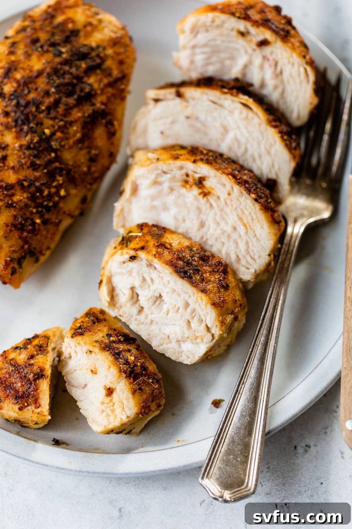 sliced cooked chicken breast on a plate with a fork, ready to be enjoyed