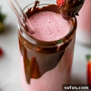 tall glass with chocolate on the inside of it filled with a strawberry smoothie