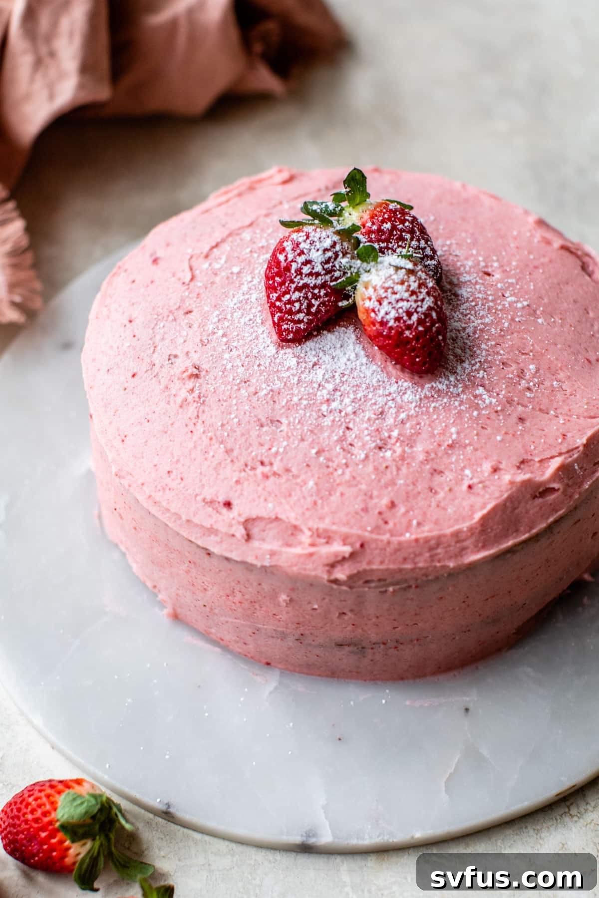 an overview of a whole strawberry cake with three strawberries sitting on top