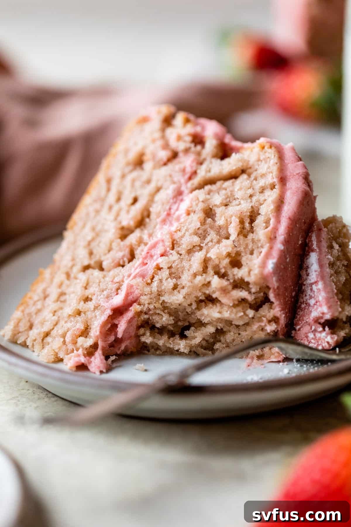 a picture of a slice of vegan strawberry cake on a plate with a bite of cake missing