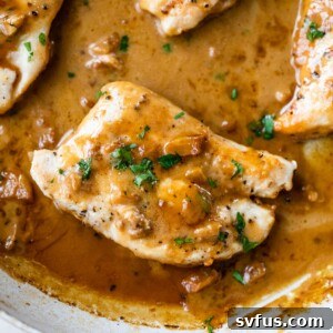 chicken breasts in a skillet with an orange and brown-colored sauce overtop