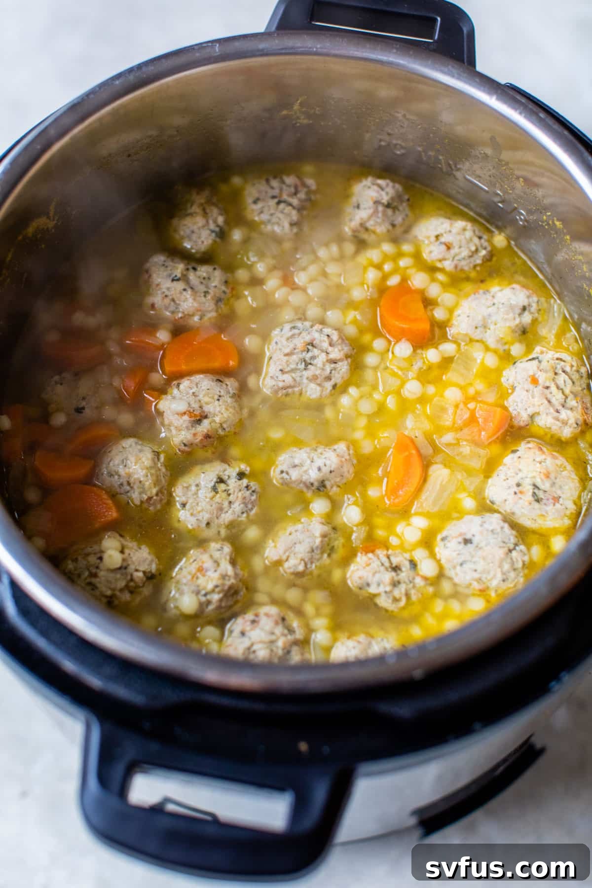 Close-up shot of an Instant Pot filled with cooked meatballs and broth, ready for the final ingredients