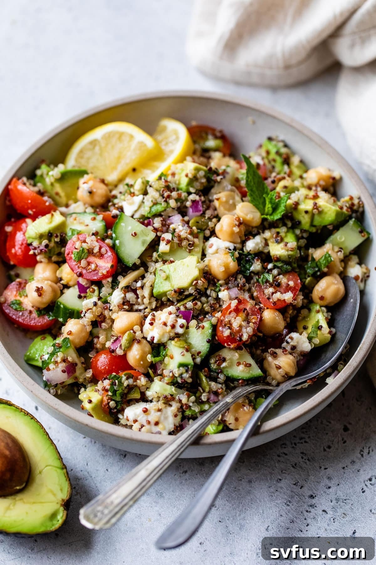 A beautifully presented bowl of Zesty Quinoa Salad, garnished with fresh herbs and a spoon, ready to be enjoyed.