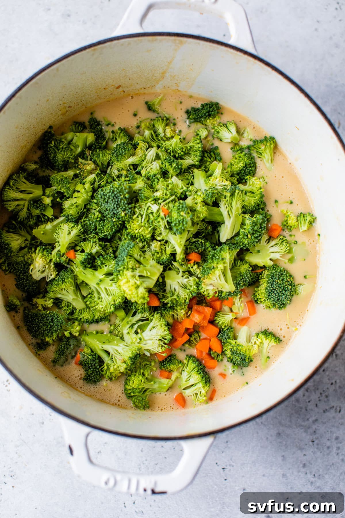 the soup pot with broccoli added on top for healthy broccoli cheddar soup