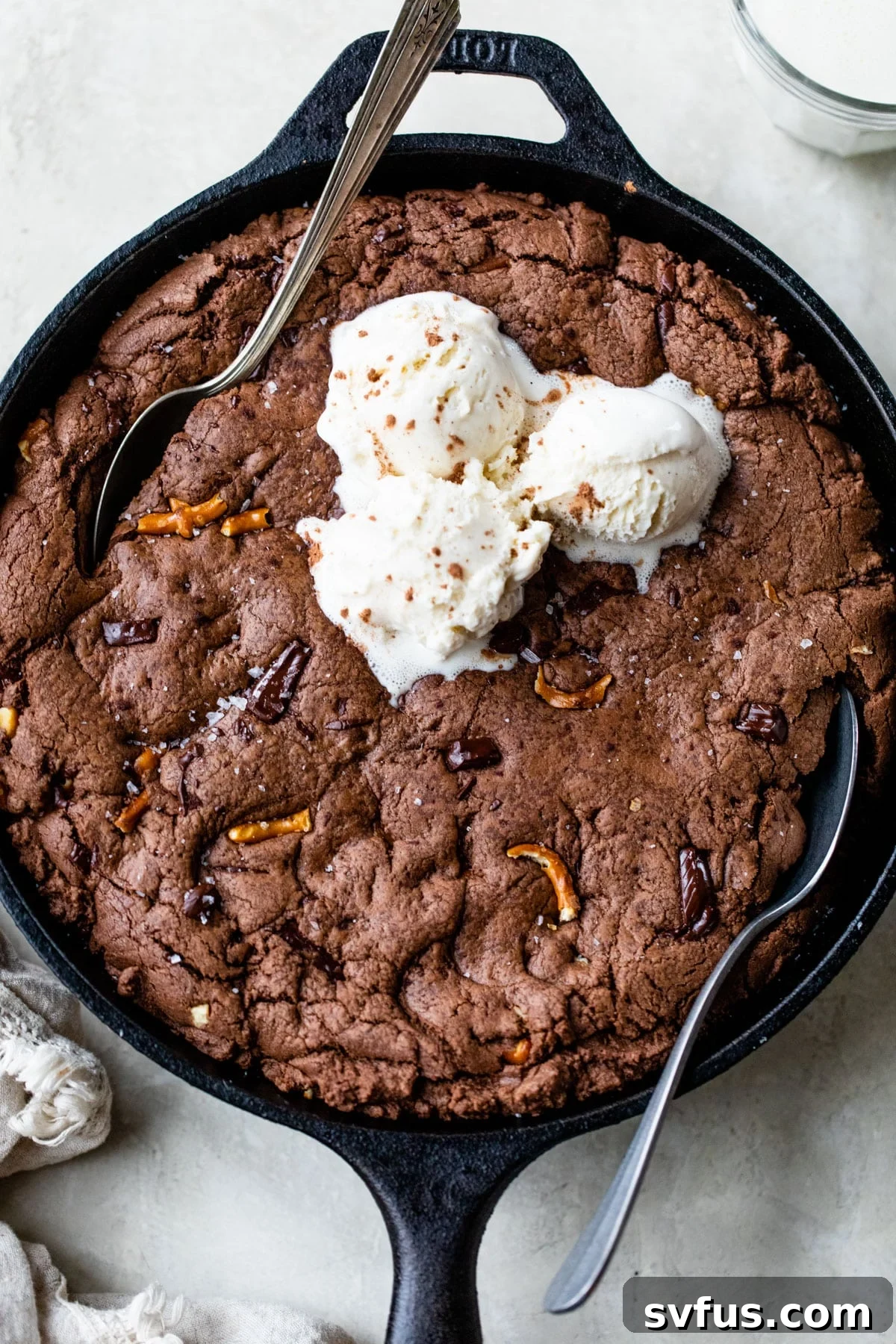 Warm double chocolate skillet cookie topped with melting vanilla ice cream in a cast iron pan