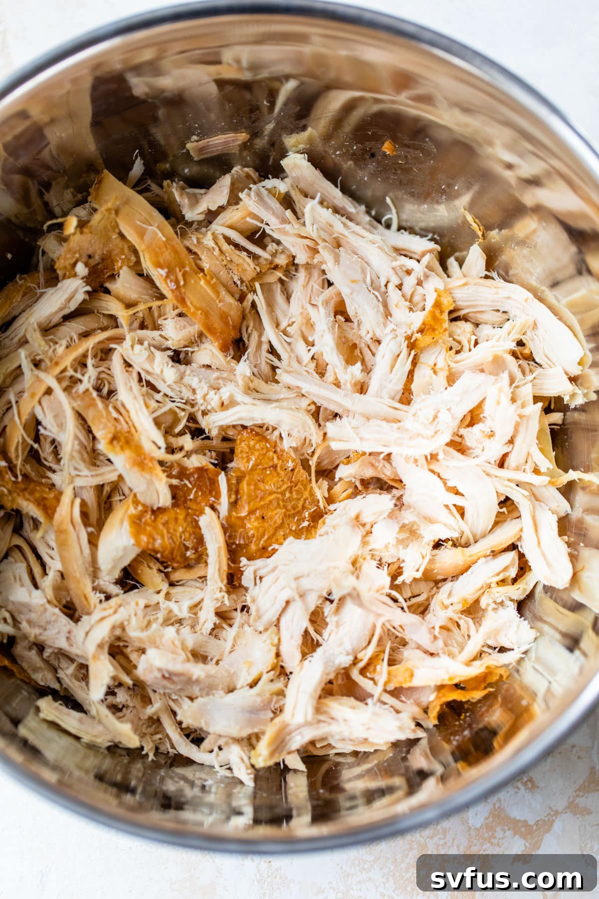 Shredded rotisserie chicken ready for tacos in a large mixing bowl