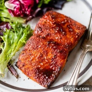 zoomed in image of cooked salmon on a plate with lettuce and a fork