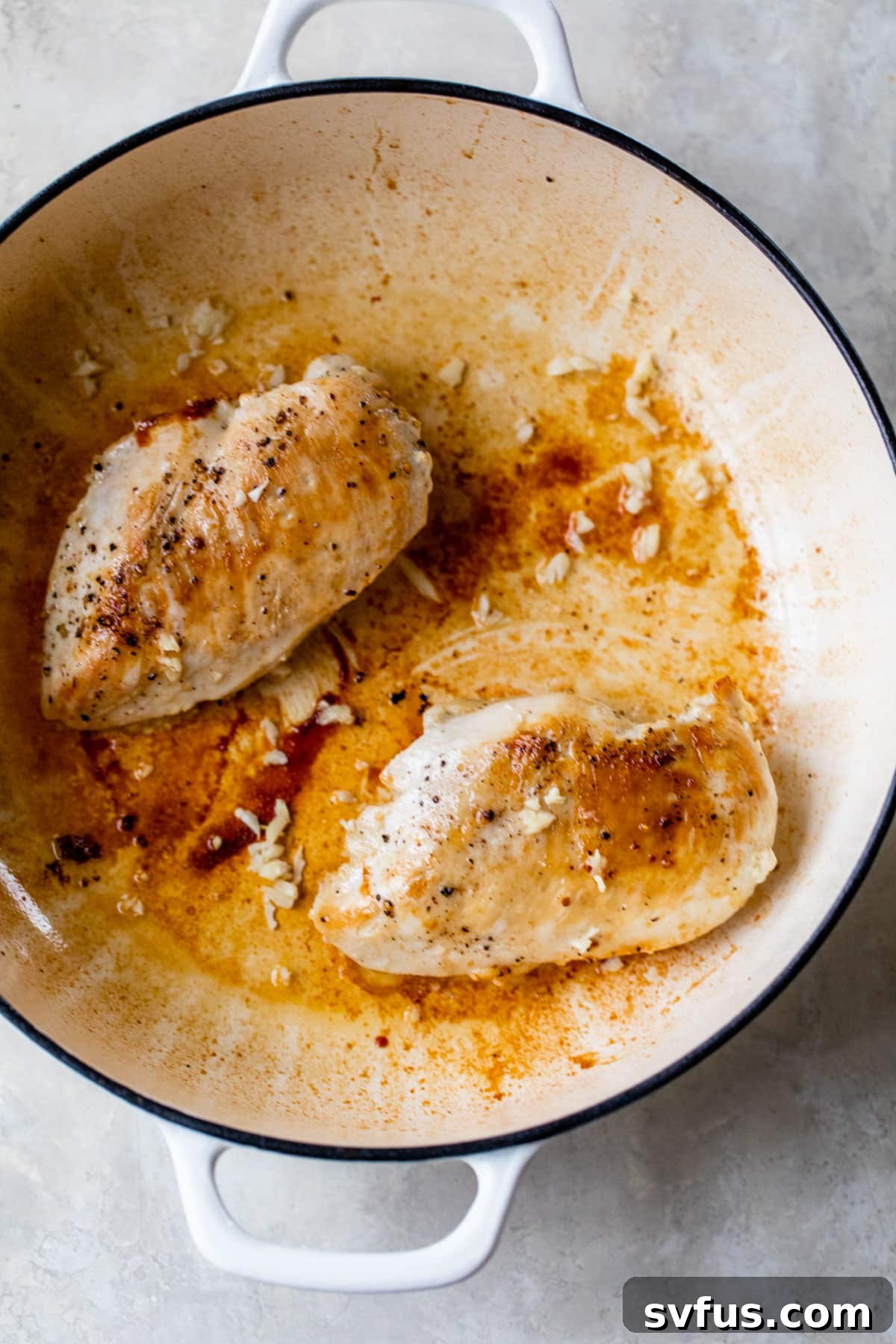 a dutch oven with 2 baked chicken breasts inside