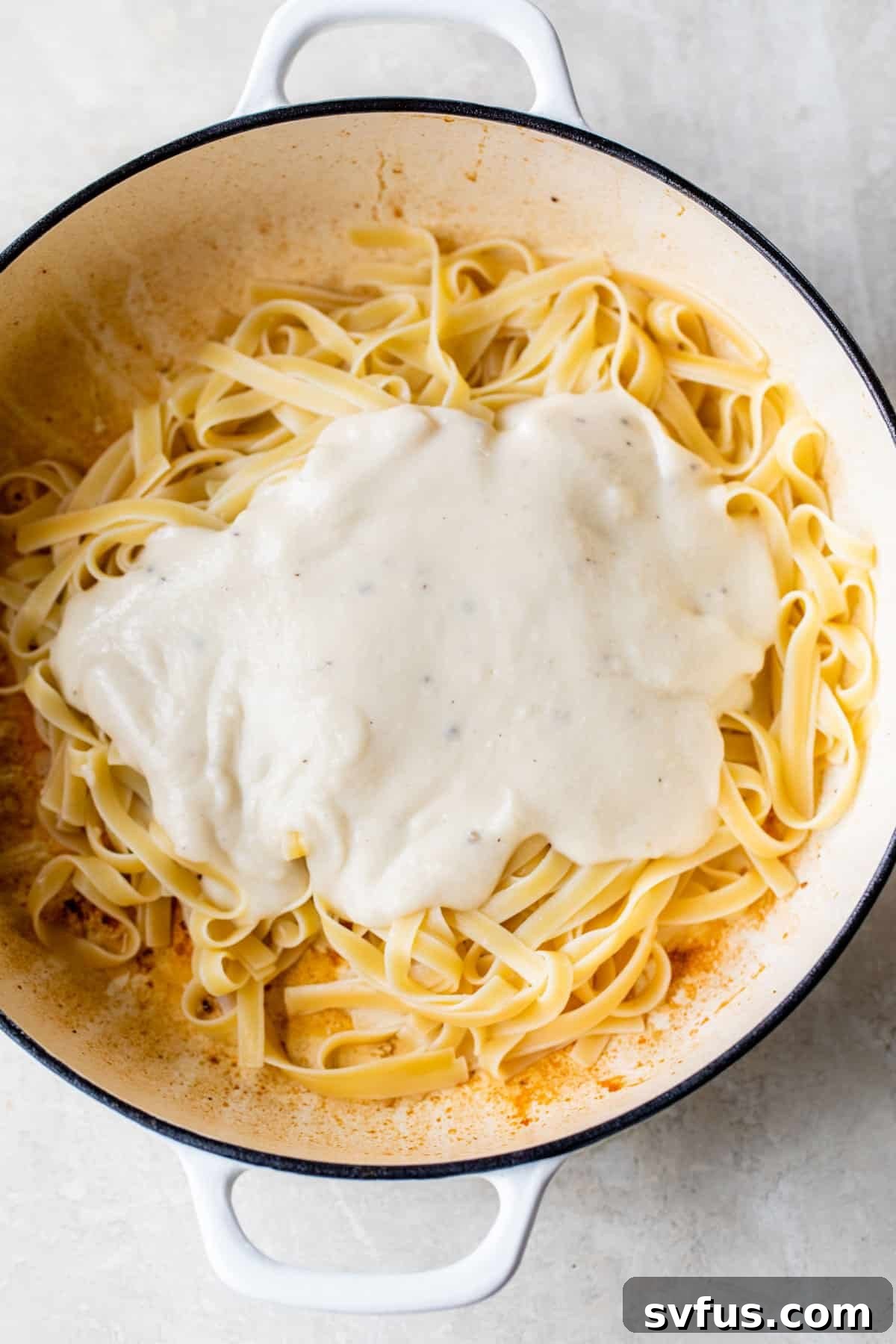 a dutch oven with fettuccine and alfredo sauce inside