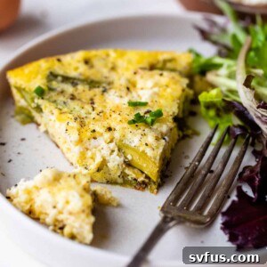 asparagus frittata on a plate with a piece cut by a fork