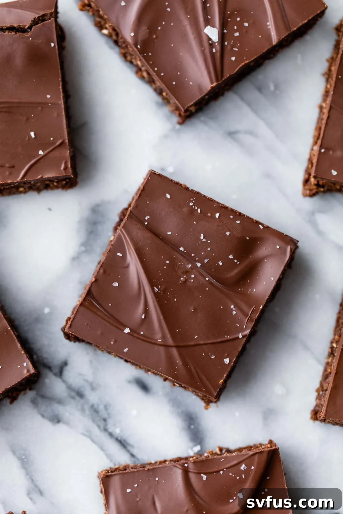 Close-up shot of individual chocolate quinoa bars topped with a sprinkle of flaky sea salt, arranged neatly on a table.