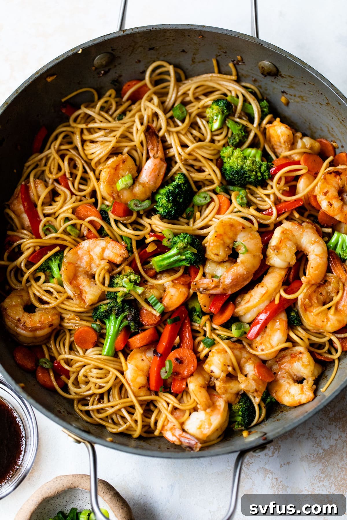 A wide shot of Shrimp Lo Mein, fully mixed with noodles and sauce, in a large skillet.