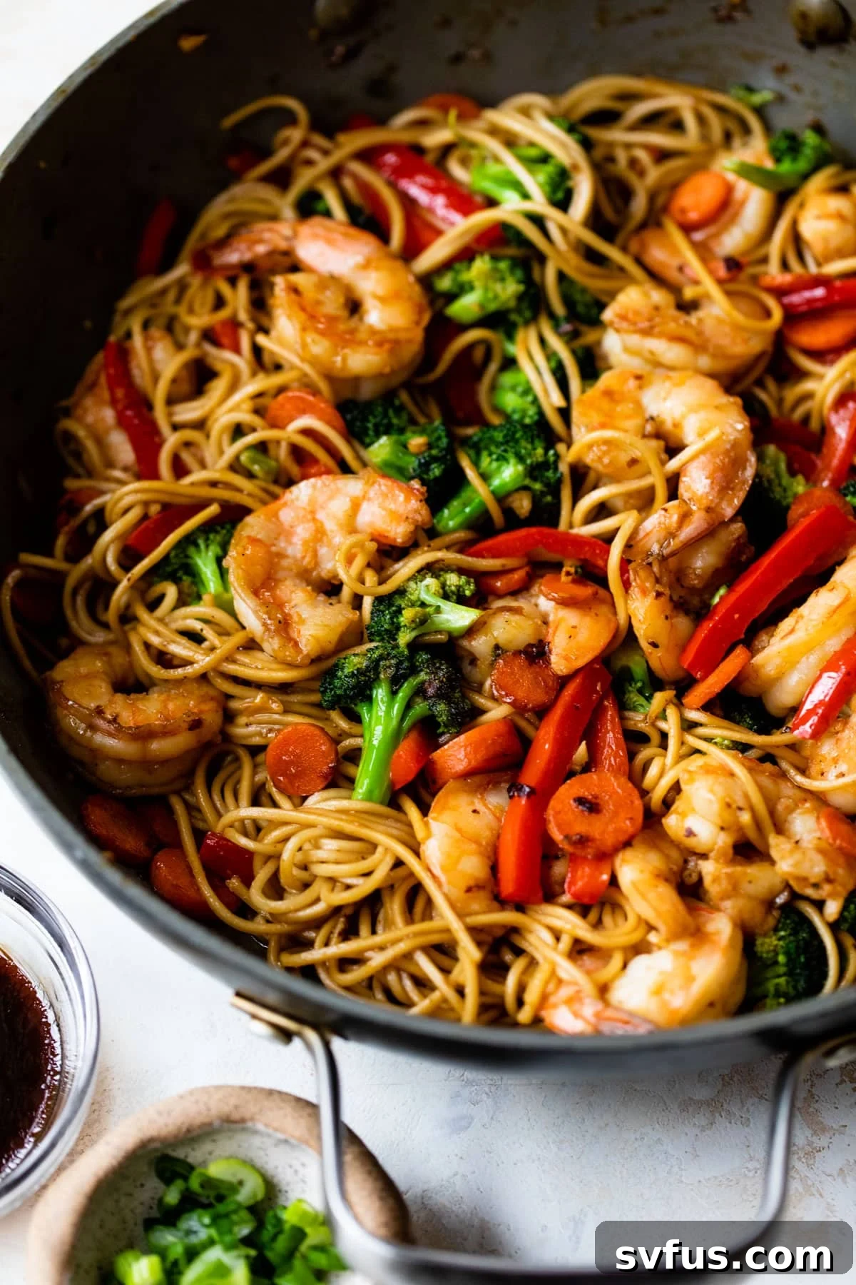 A close-up view of vibrant Shrimp Lo Mein with colorful vegetables and noodles in a skillet.