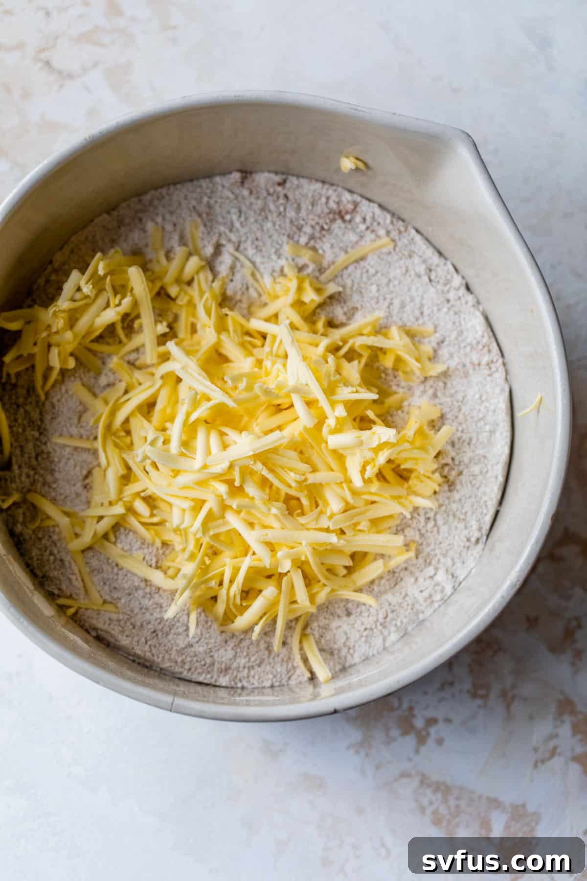 dry ingredients in a bowl with grated butter on top