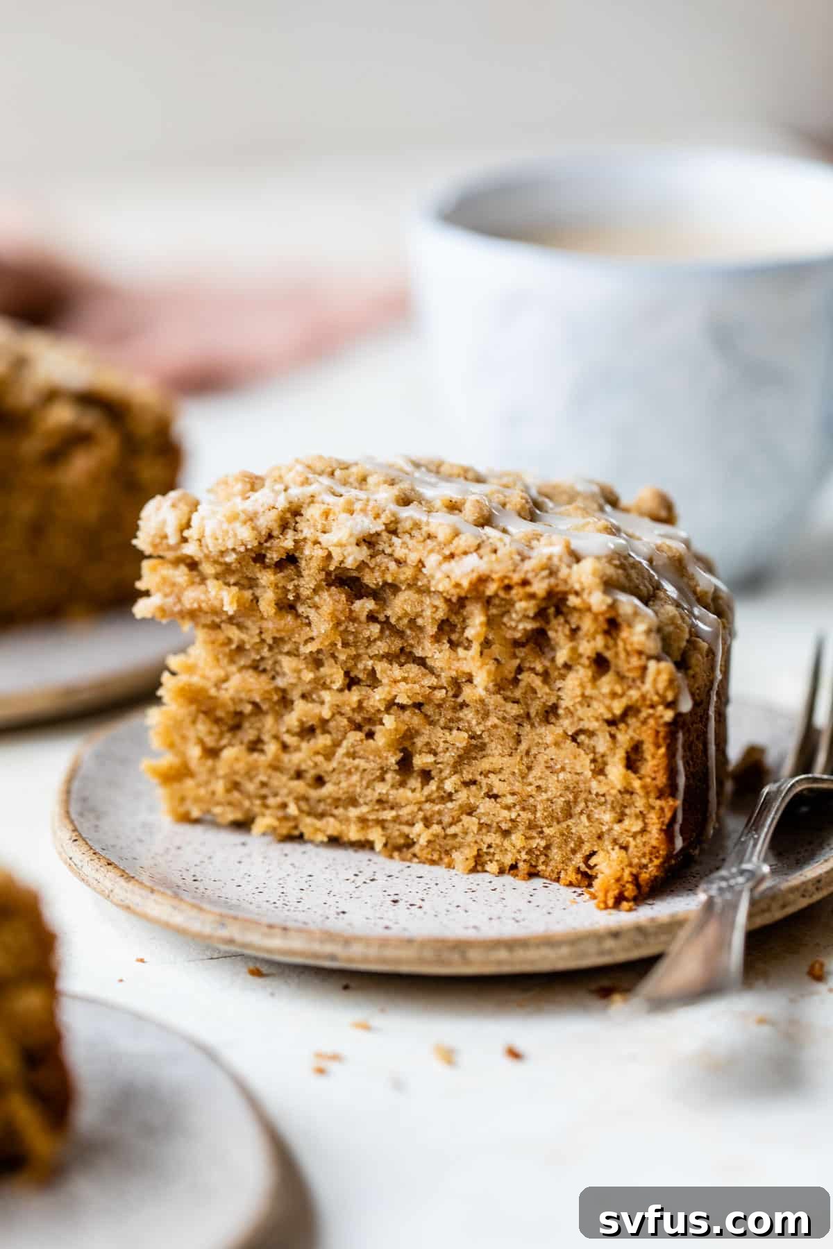 a side shot of a slice of vegan coffee cake on a plate with a fork