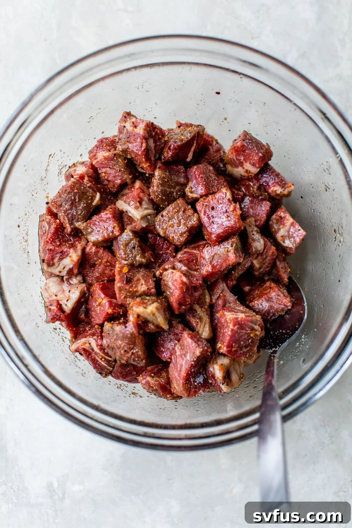 Raw steak bites seasoned in a bowl, ready for the air fryer.