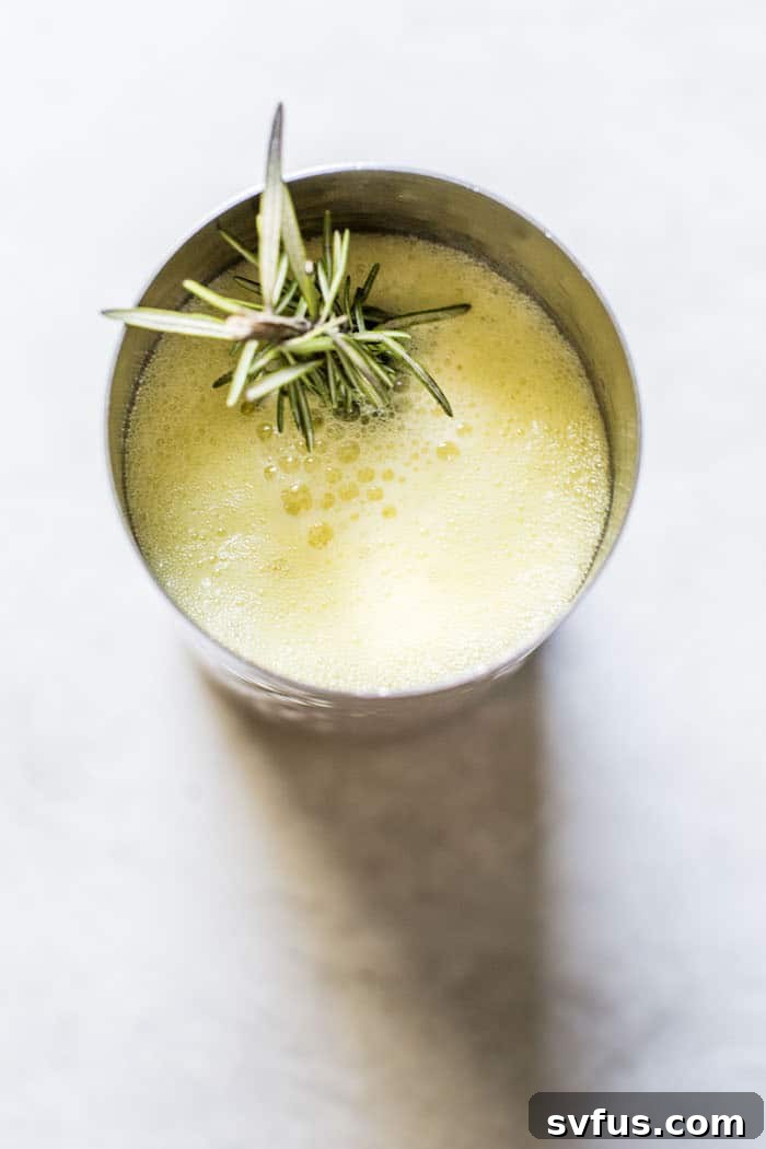Close-up of Pineapple Ginger Punch with ice and rosemary garnish