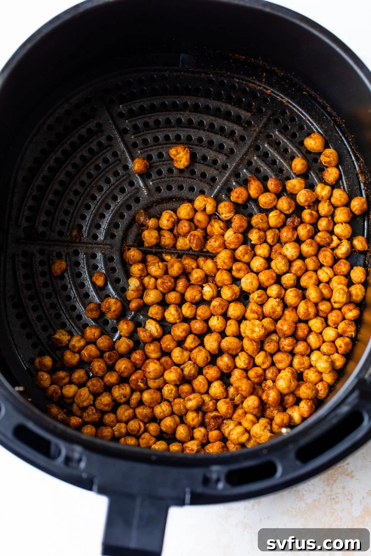 Seasoned chickpeas being roasted to crispy perfection in an air fryer basket.