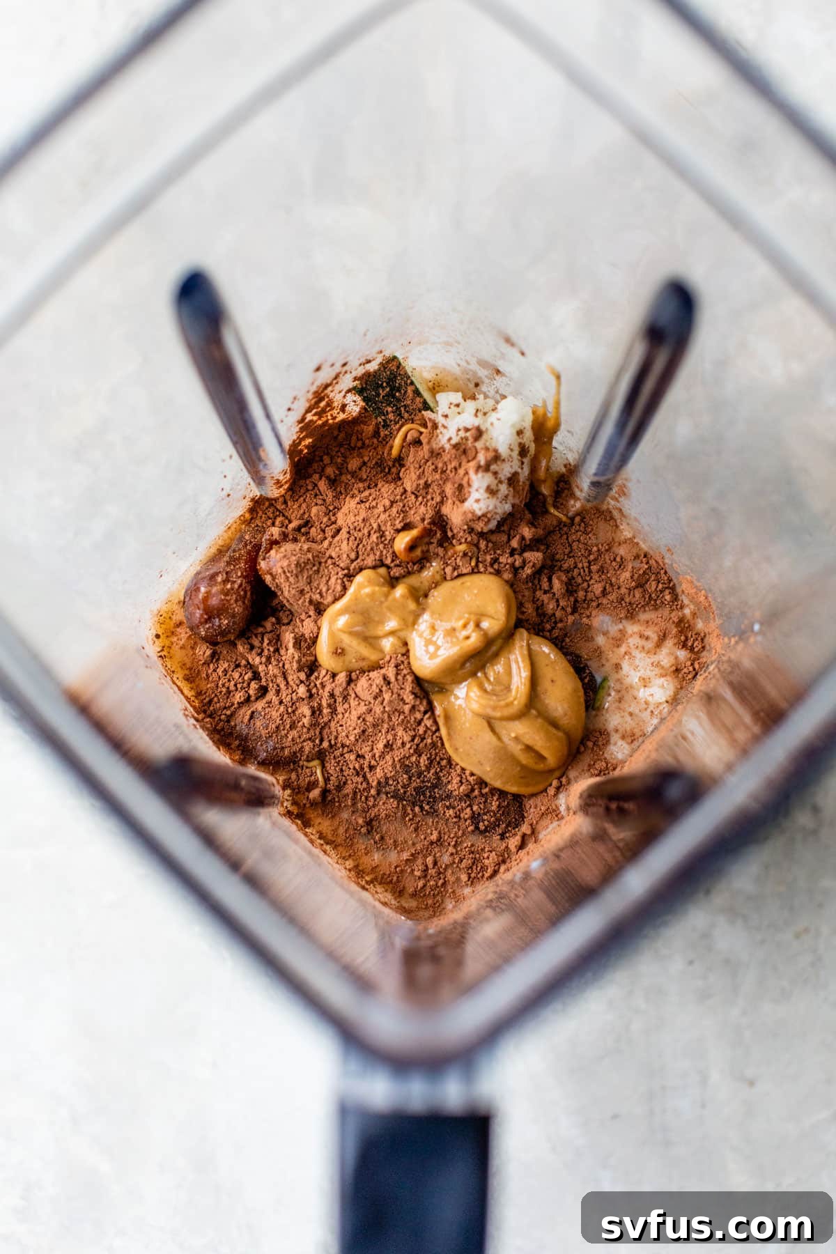 All smoothie ingredients thoughtfully added into a high-powered blender, ready for blending