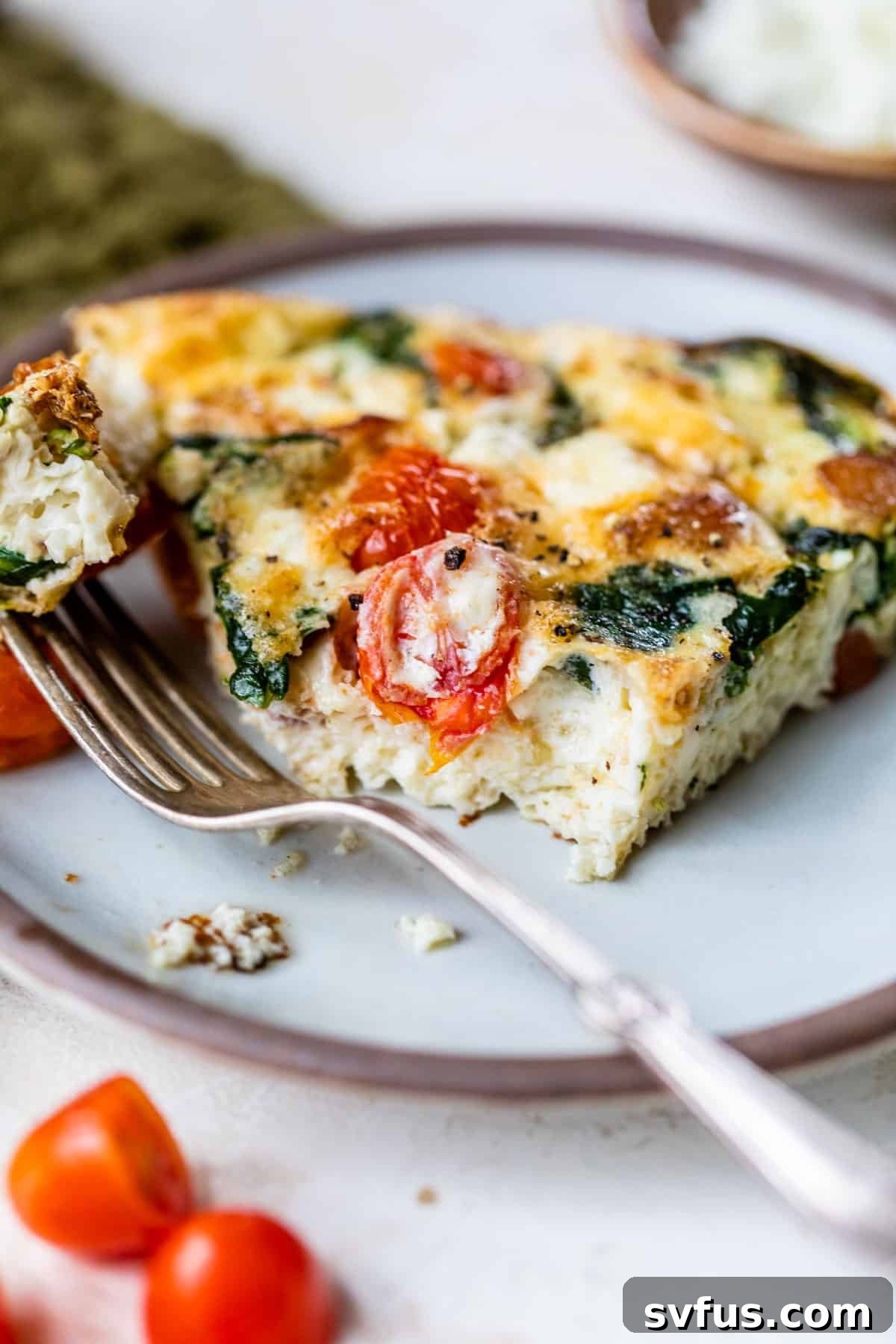 A second view of a slice of egg white frittata on a plate with a fork, emphasizing its fluffy texture.