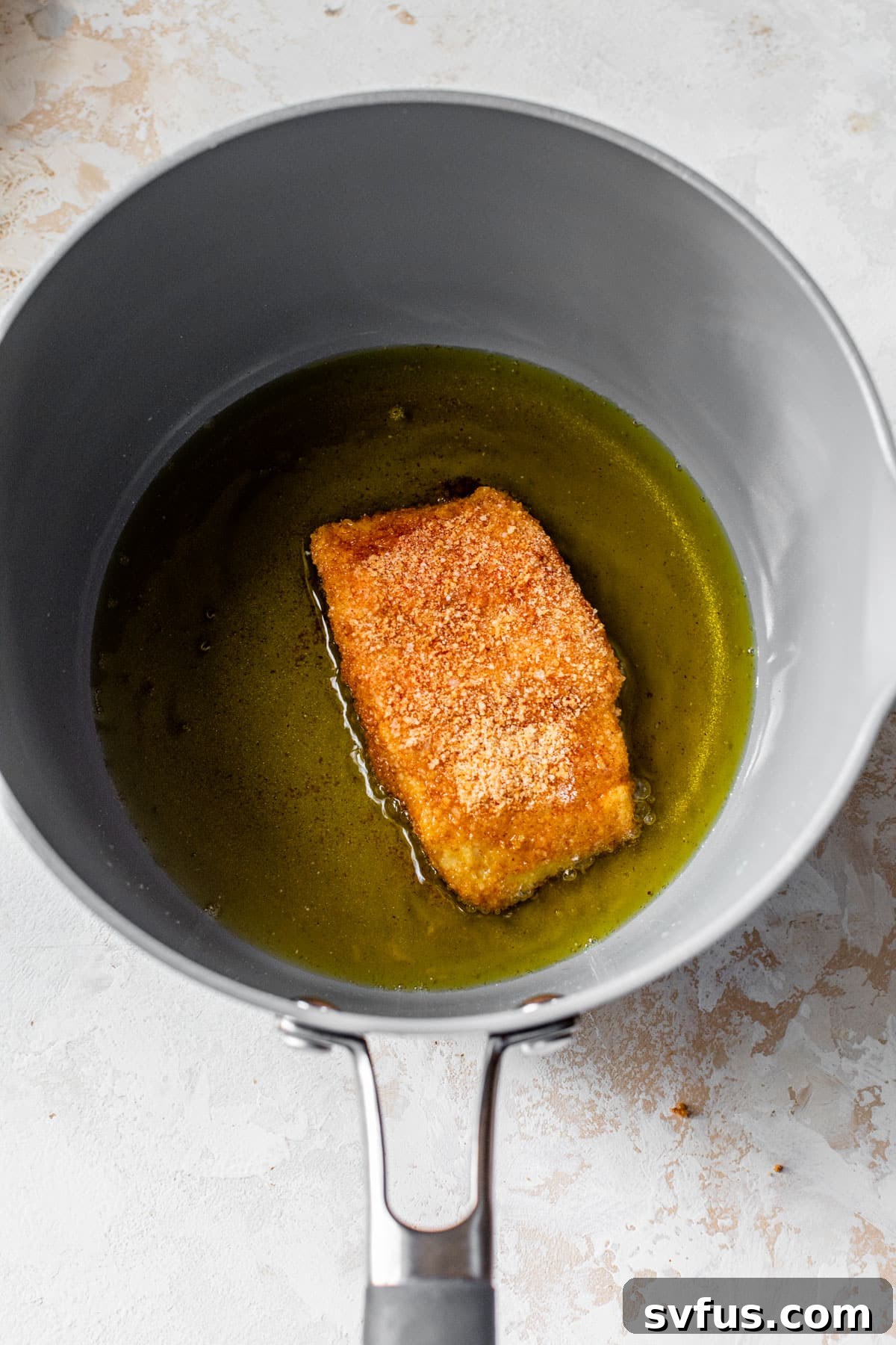 breaded cod being fried in hot oil in a skillet