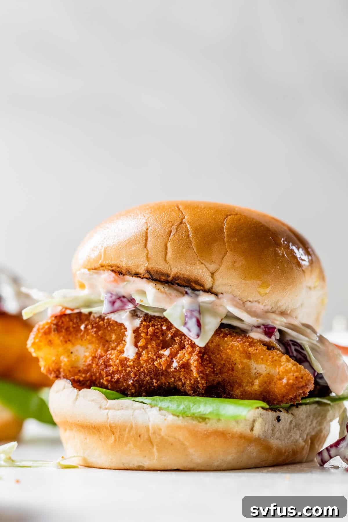 fried cod sandwich with coleslaw and sauce on a bun