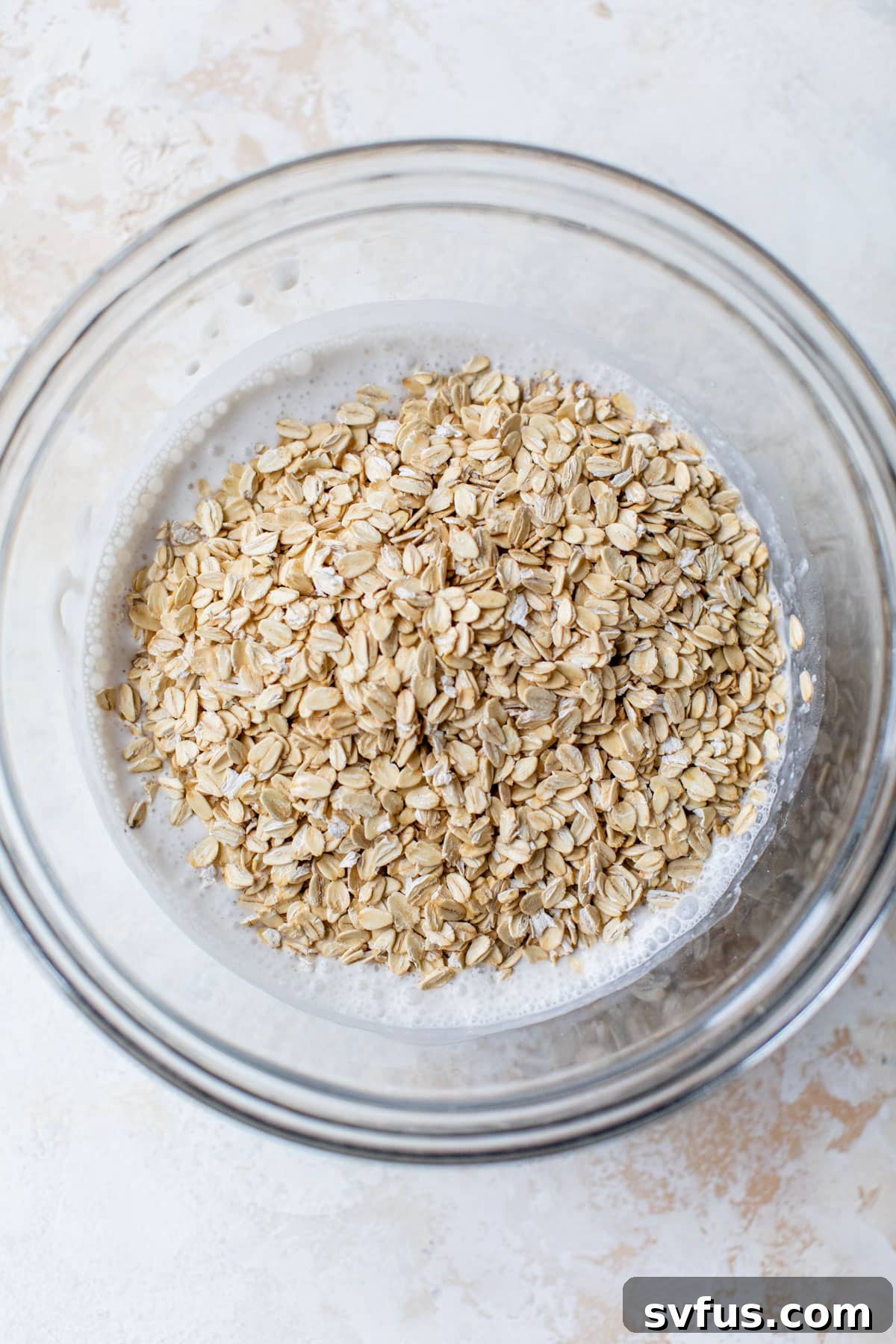 yogurt and milk mixed together in a large glass bowl with oats added on top