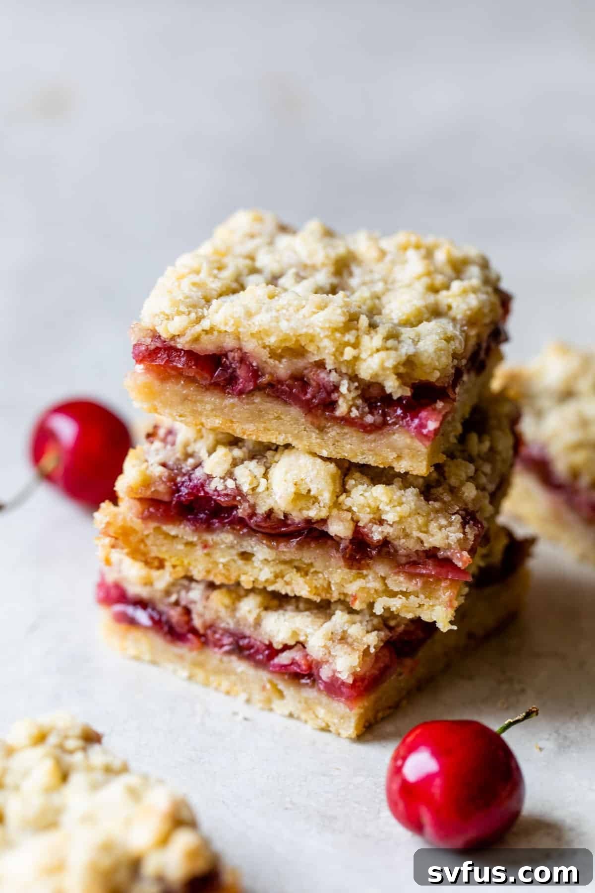 A stack of three homemade cherry crumb bars, showcasing their buttery crust, sweet cherry filling, and golden crumb topping. Ideal for summer desserts or any special occasion.
