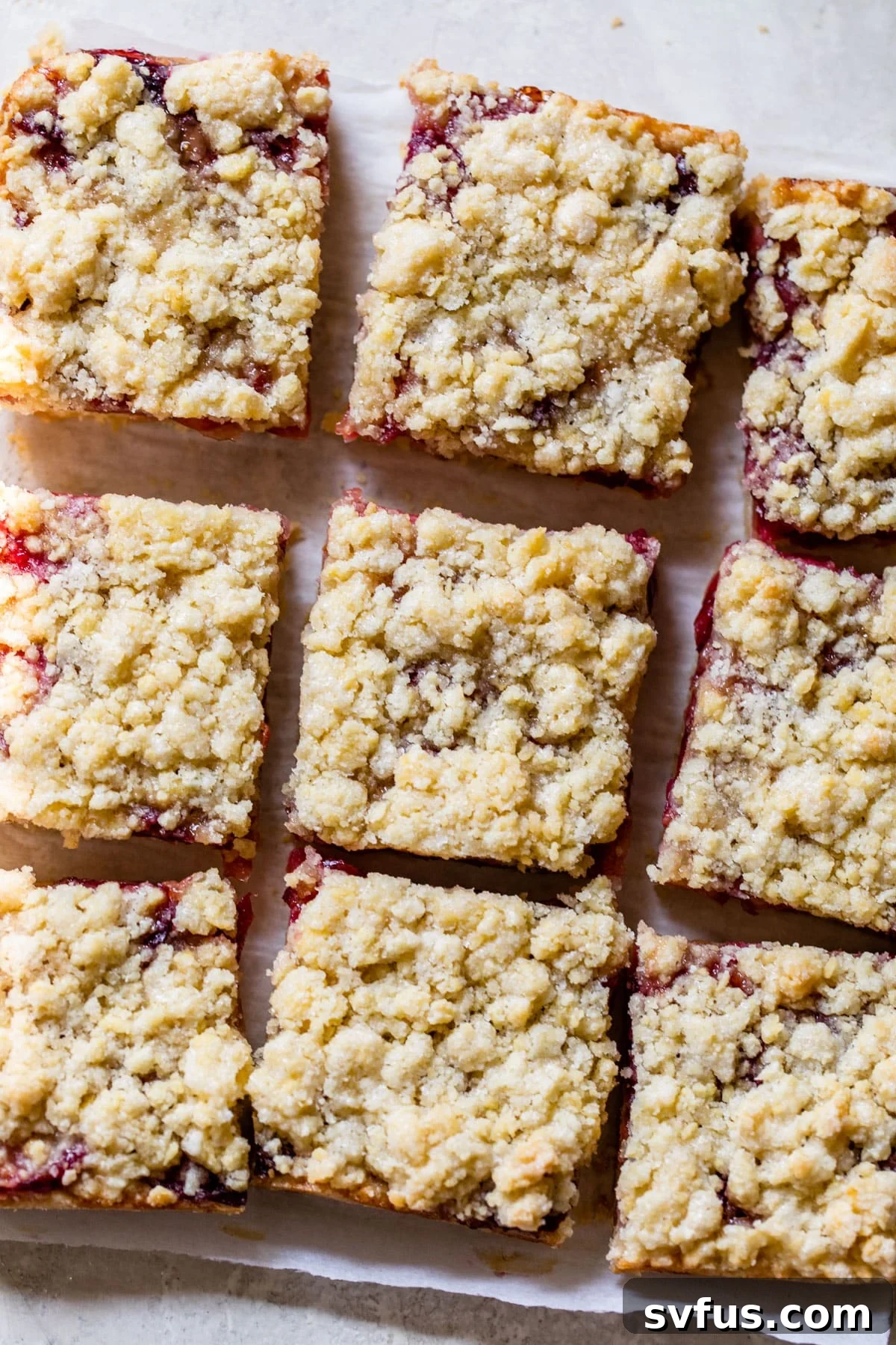 Golden-brown cherry crumb bars cooling on parchment paper, ready to be sliced and served.