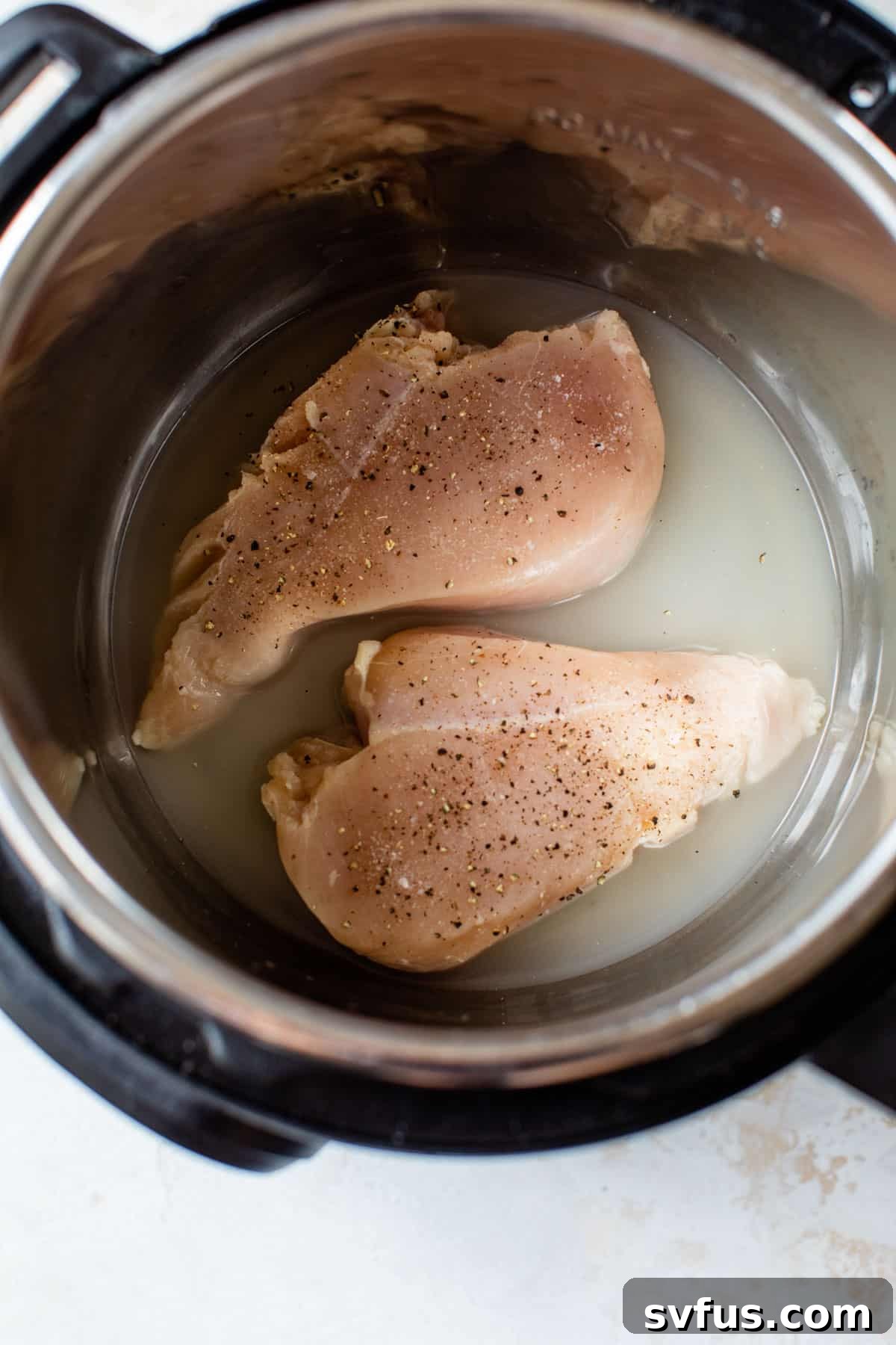 Two raw chicken breasts seasoned with salt and pepper, ready for cooking.