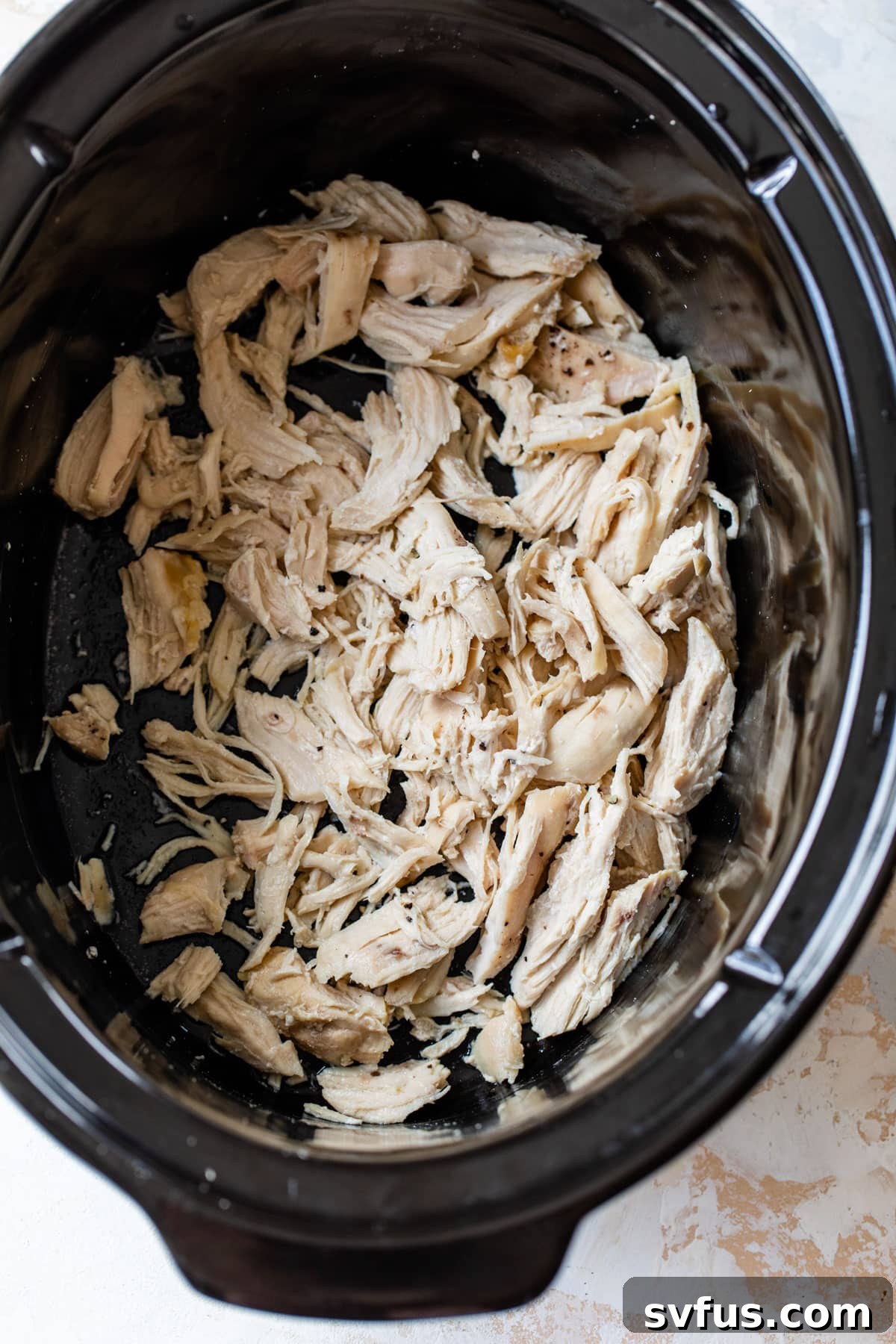 Tender, cooked chicken breasts inside a slow cooker, ready to be shredded.