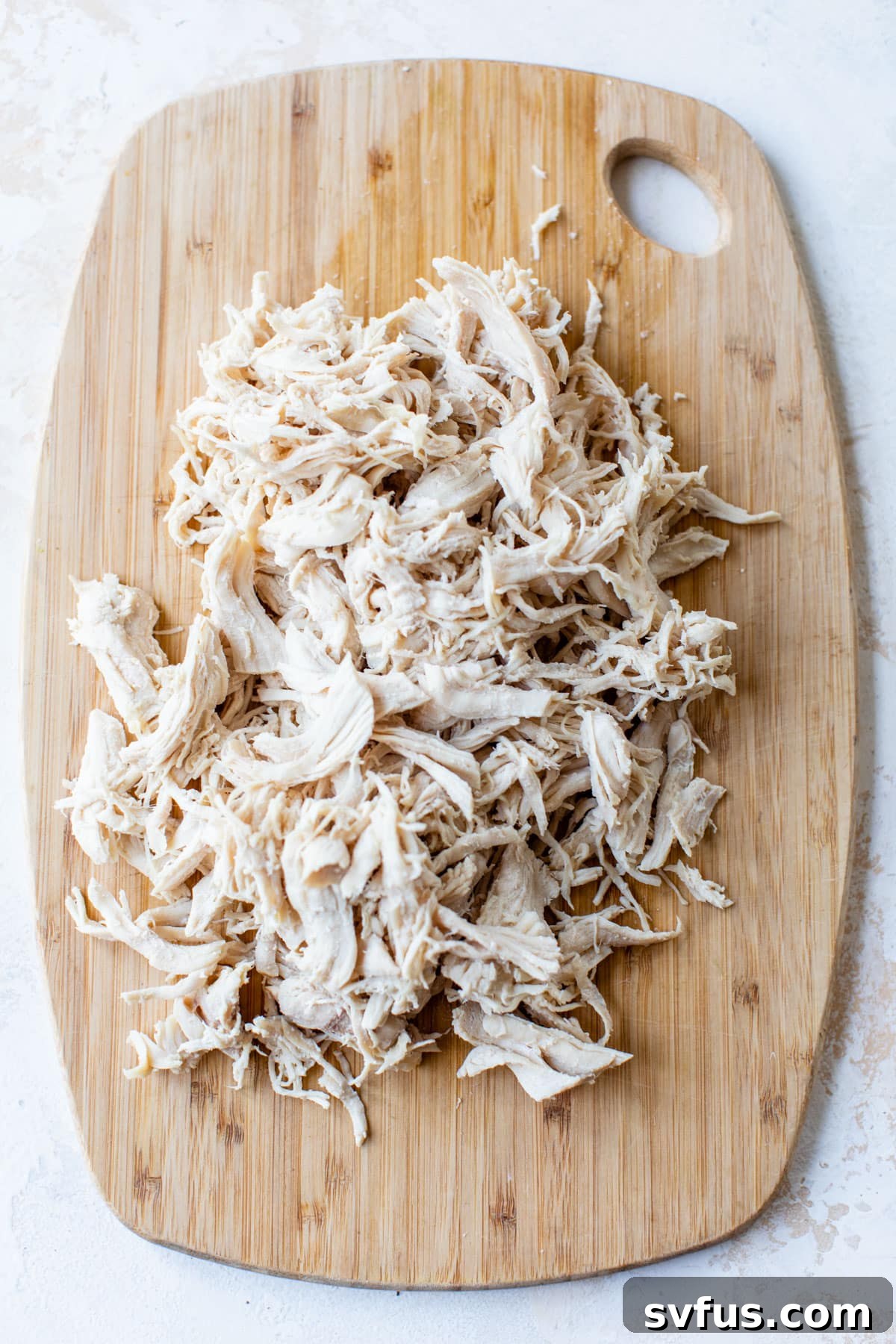 A pile of freshly shredded chicken on a cutting board, ready for use.