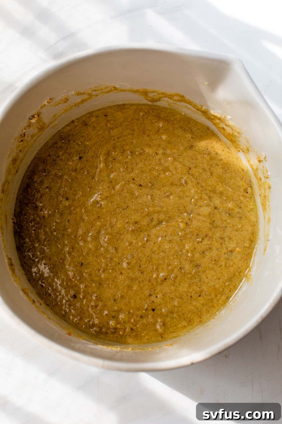 Lush green pistachio cake batter in a mixing bowl, ready for baking, showcasing its natural vibrant color and smooth consistency.