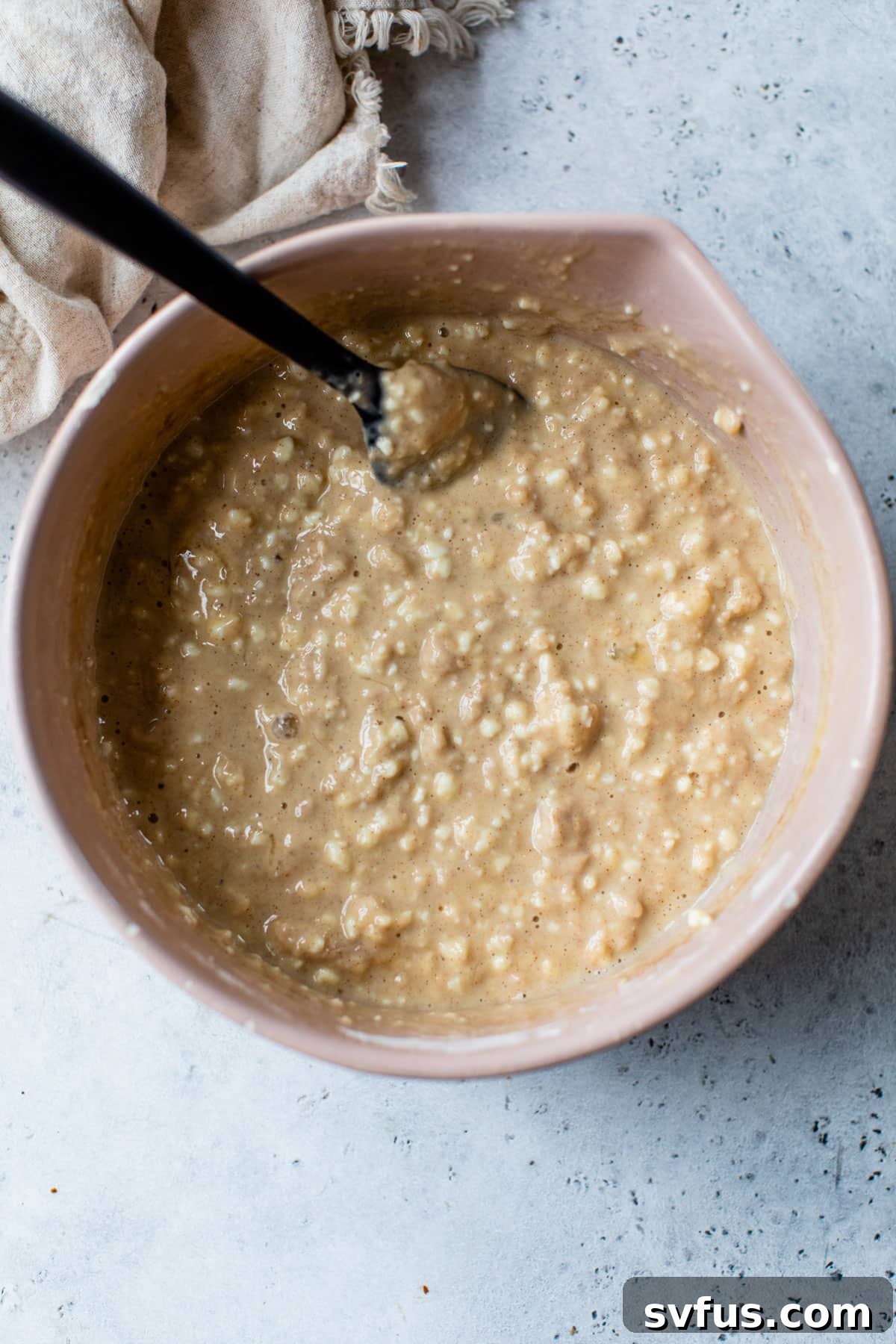 A large bowl containing the pancake batter, showing a smooth, slightly lumpy consistency as dry and wet ingredients are gently mixed.