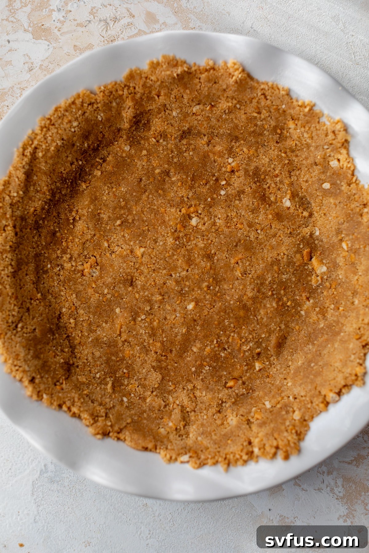 A golden brown pretzel pie crust, perfectly pressed into a round pie dish, ready for filling.