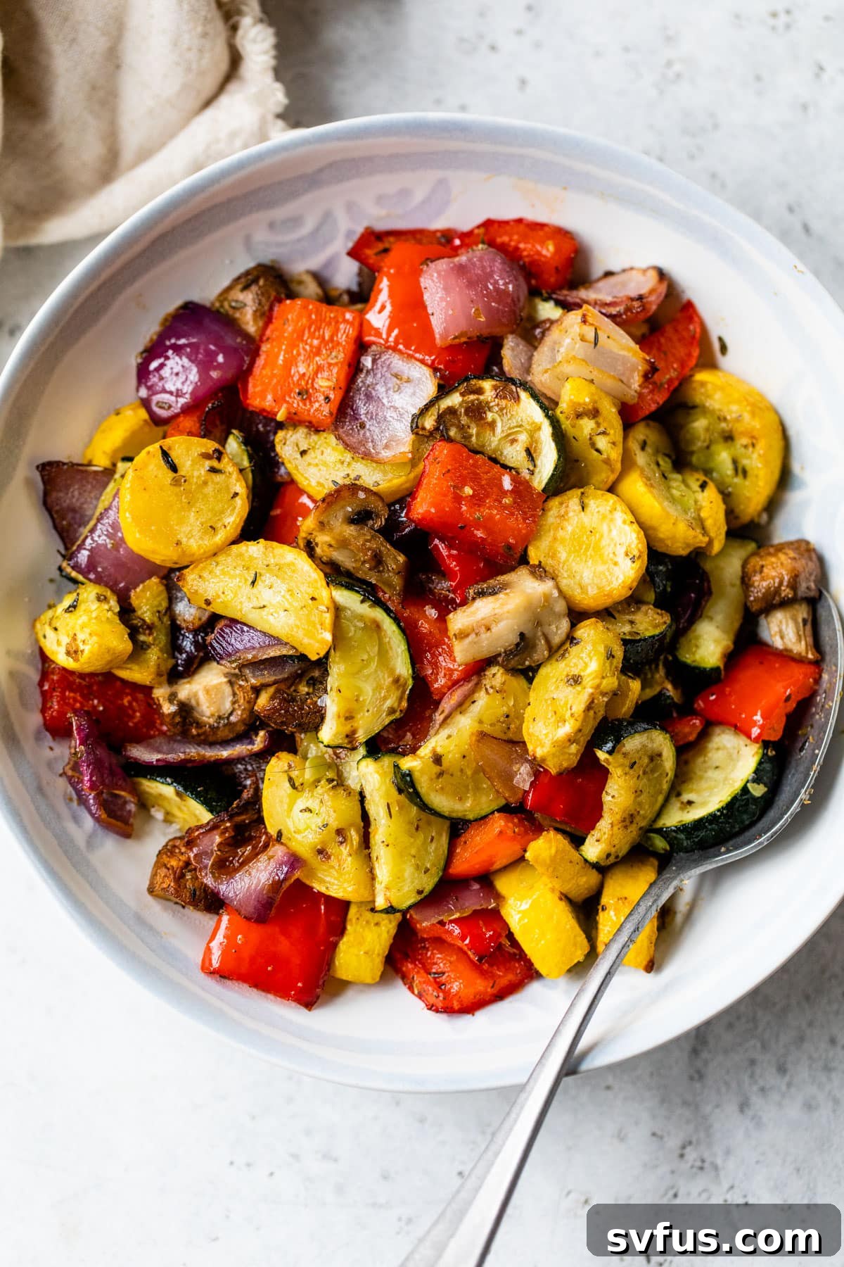 An inviting overhead shot of a generous serving of air fryer roasted vegetables, beautifully arranged in a bowl with a spoon ready for serving.