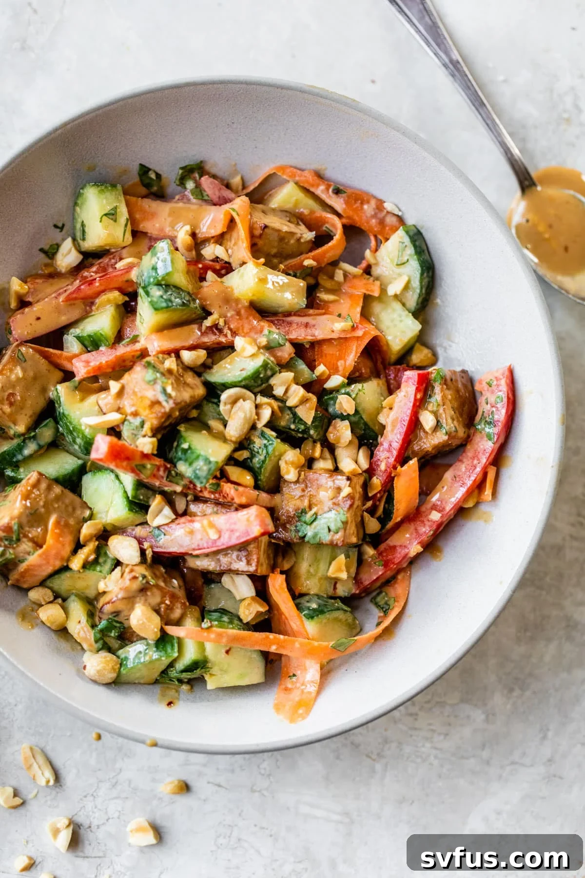 A vibrant bowl of crispy peanut tofu salad with fresh vegetables and a creamy peanut dressing.