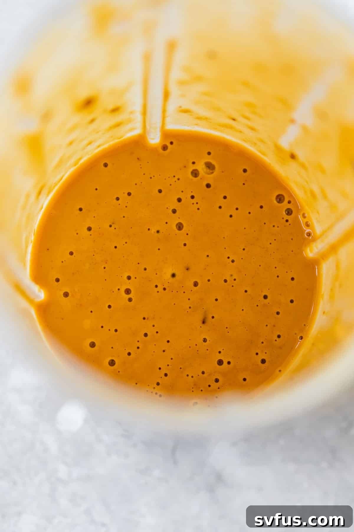 A small blender containing creamy peanut sauce, ready to be poured.