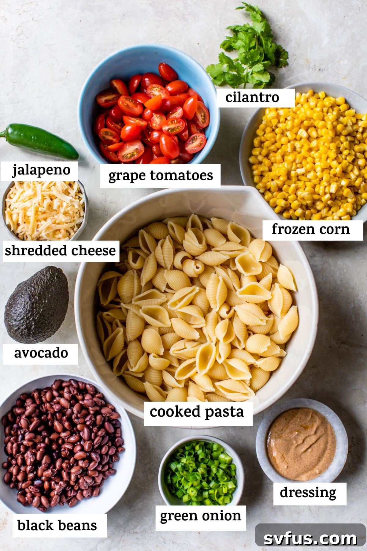 a list of all of the ingredients in the taco pasta salad: jalapeno, grape tomatoes, cilantro, frozen corn, shredded cheese, avocado, cooked pasta, black beans, green onion, and dressing