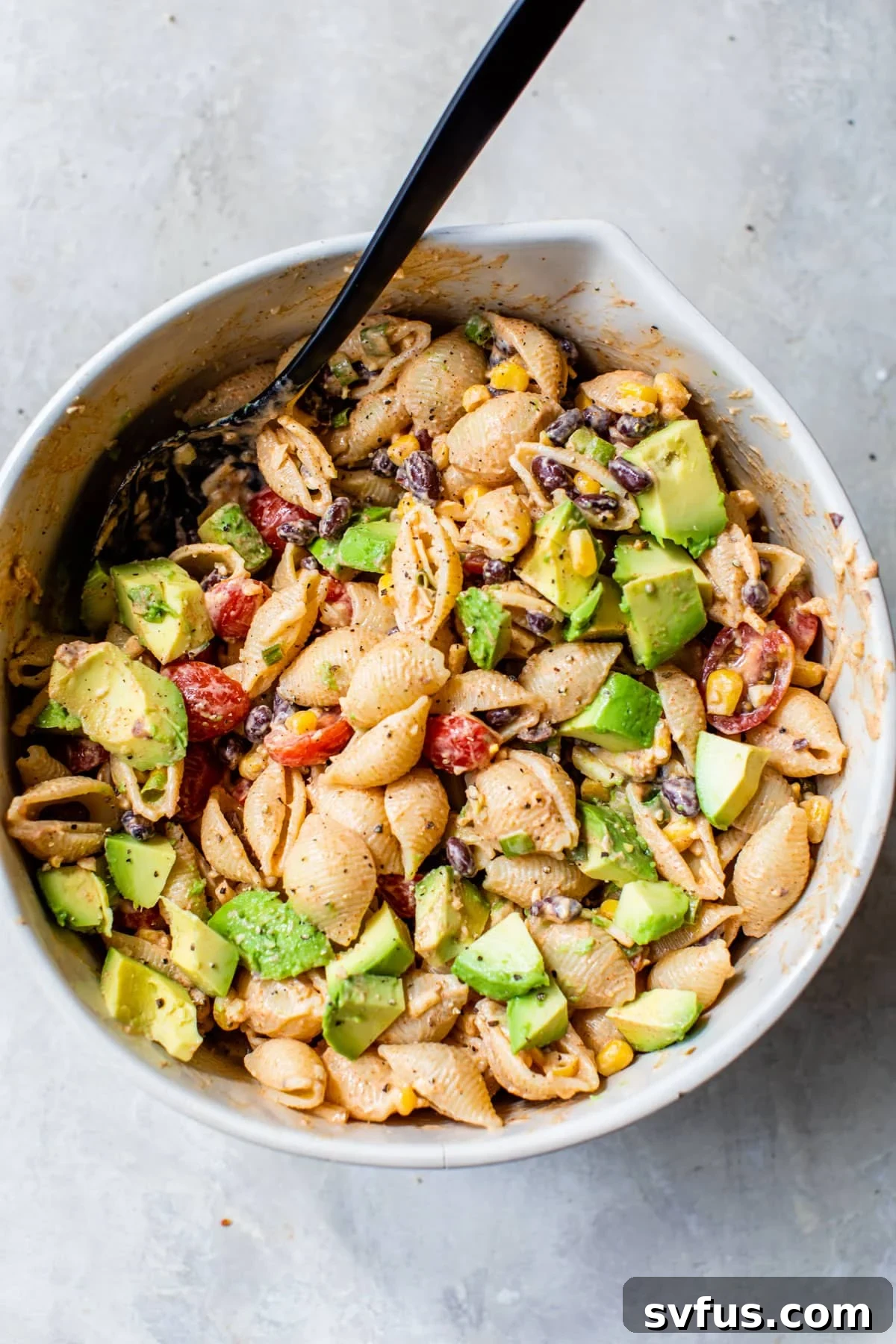 an overview of taco pasta salad in a large bowl with a mixing spoon