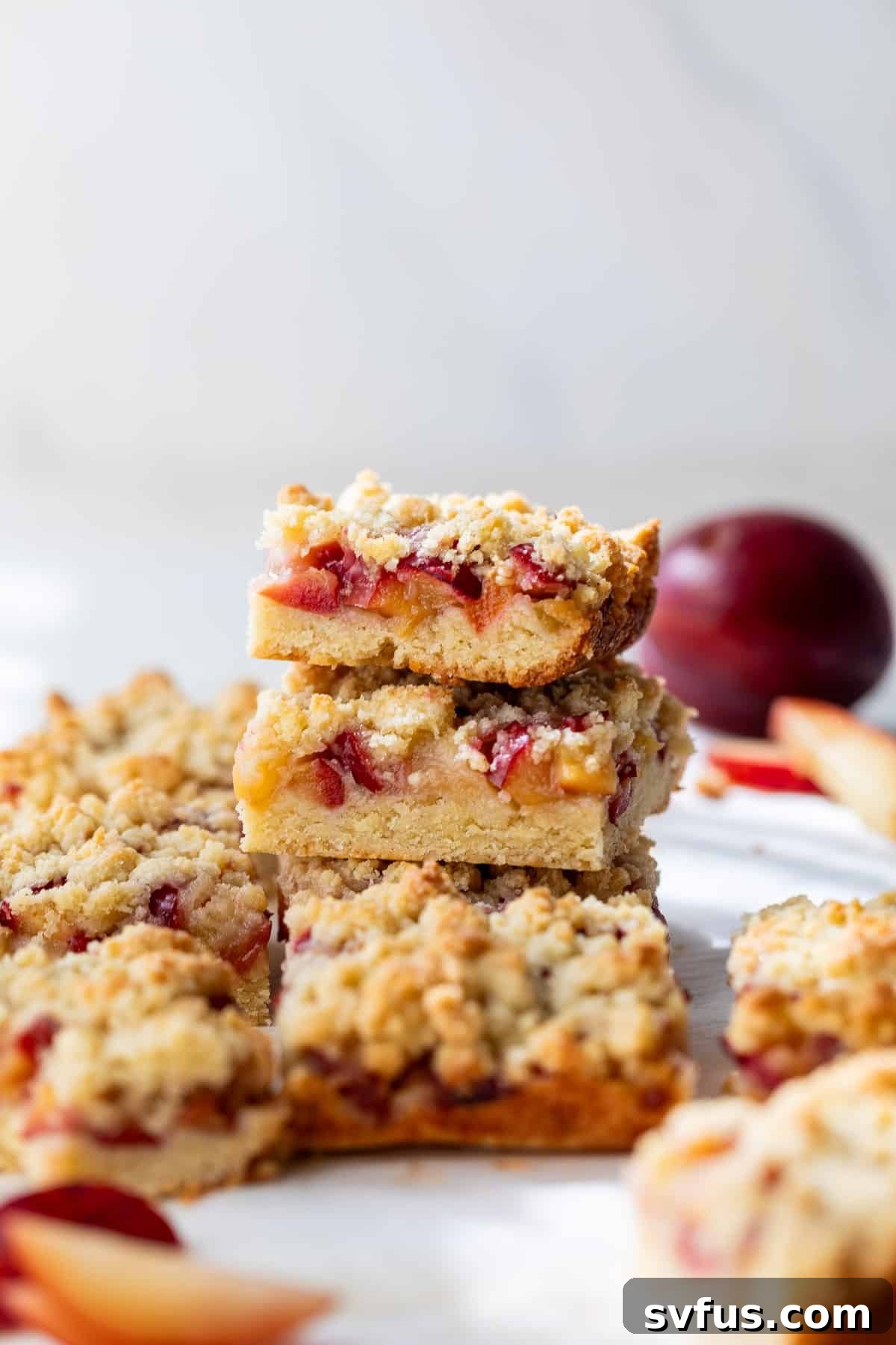 A delightful stack of golden-brown plum crumb bars, showcasing the distinct layers of crust, filling, and topping.