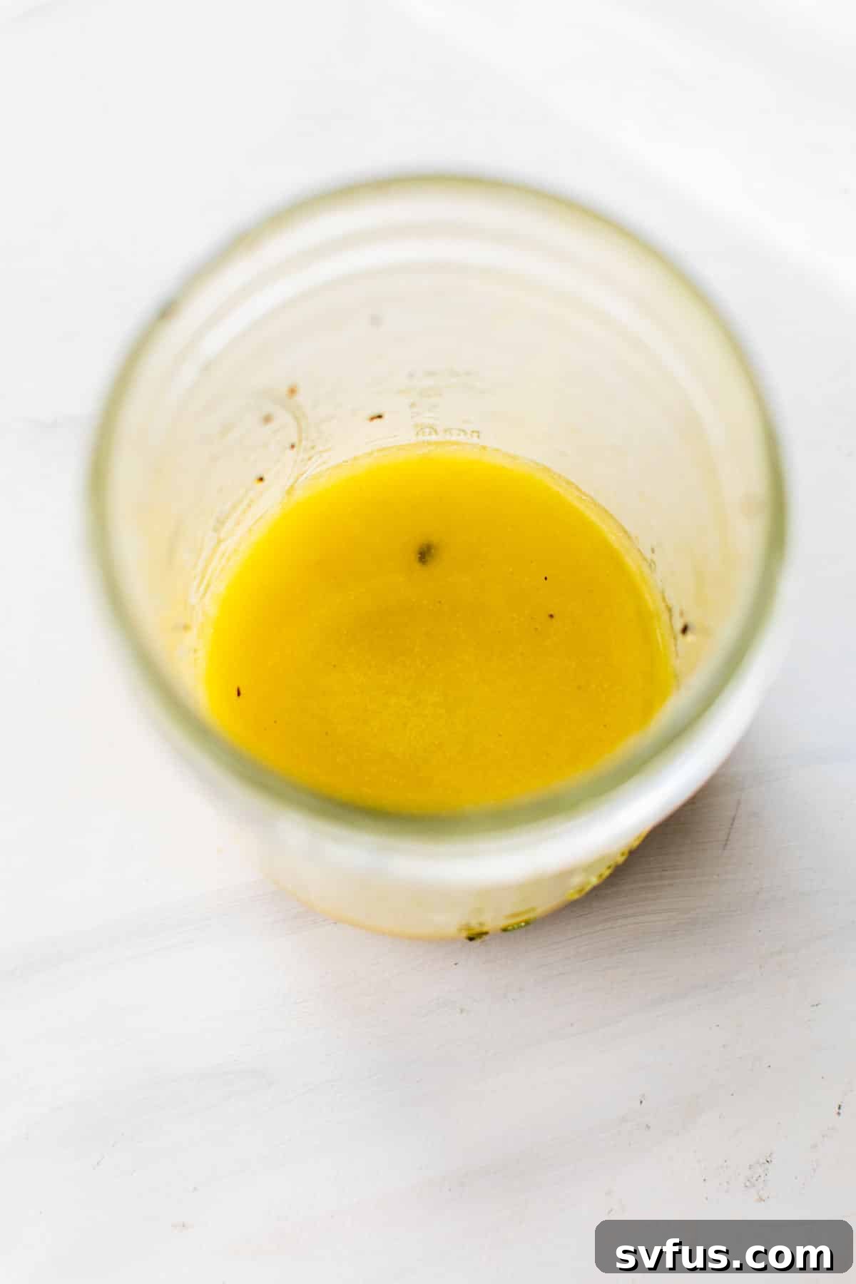 A mason jar filled with the freshly prepared zesty Mediterranean dressing.