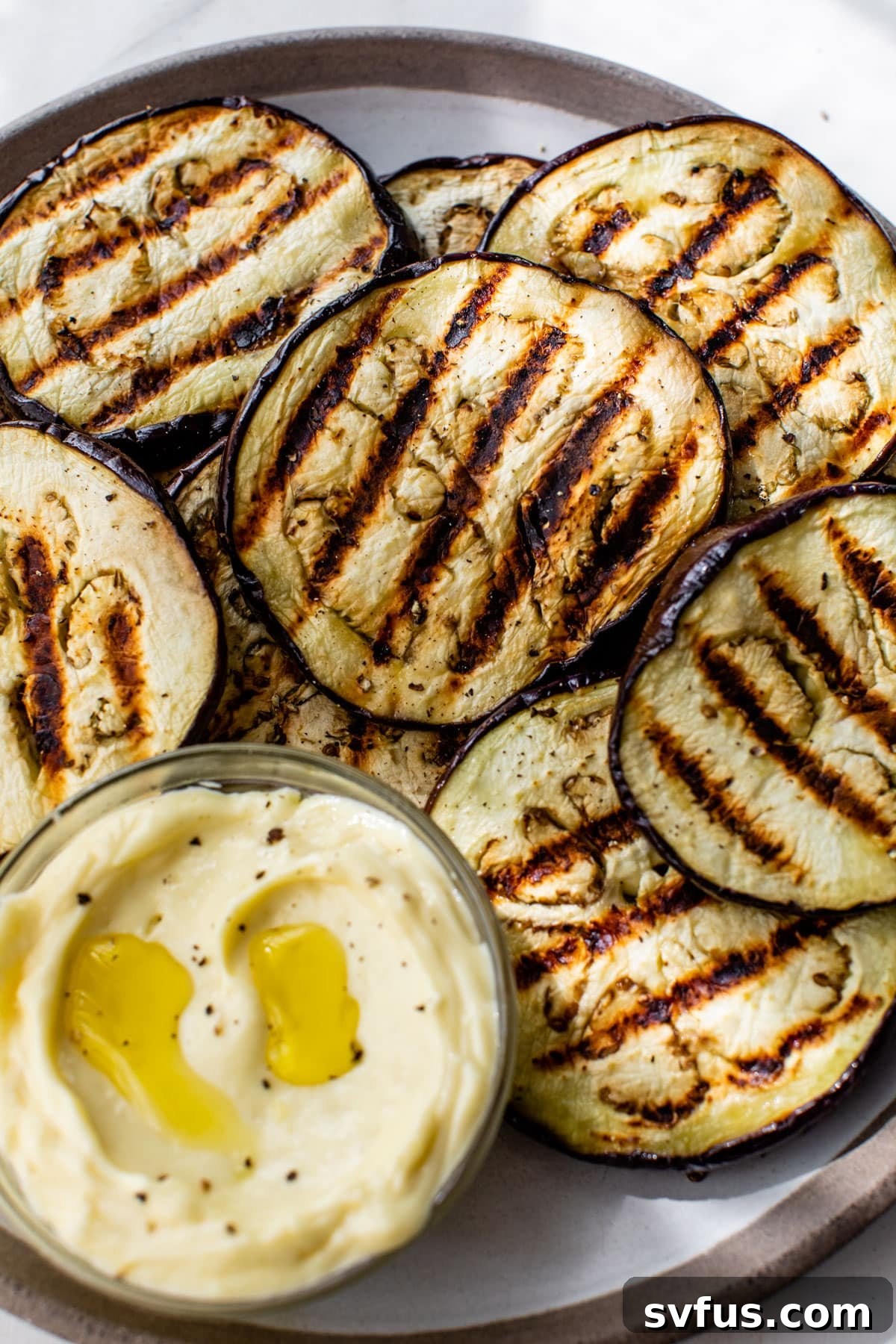 grilled eggplant rounds on a plate with garlic aioli on the side